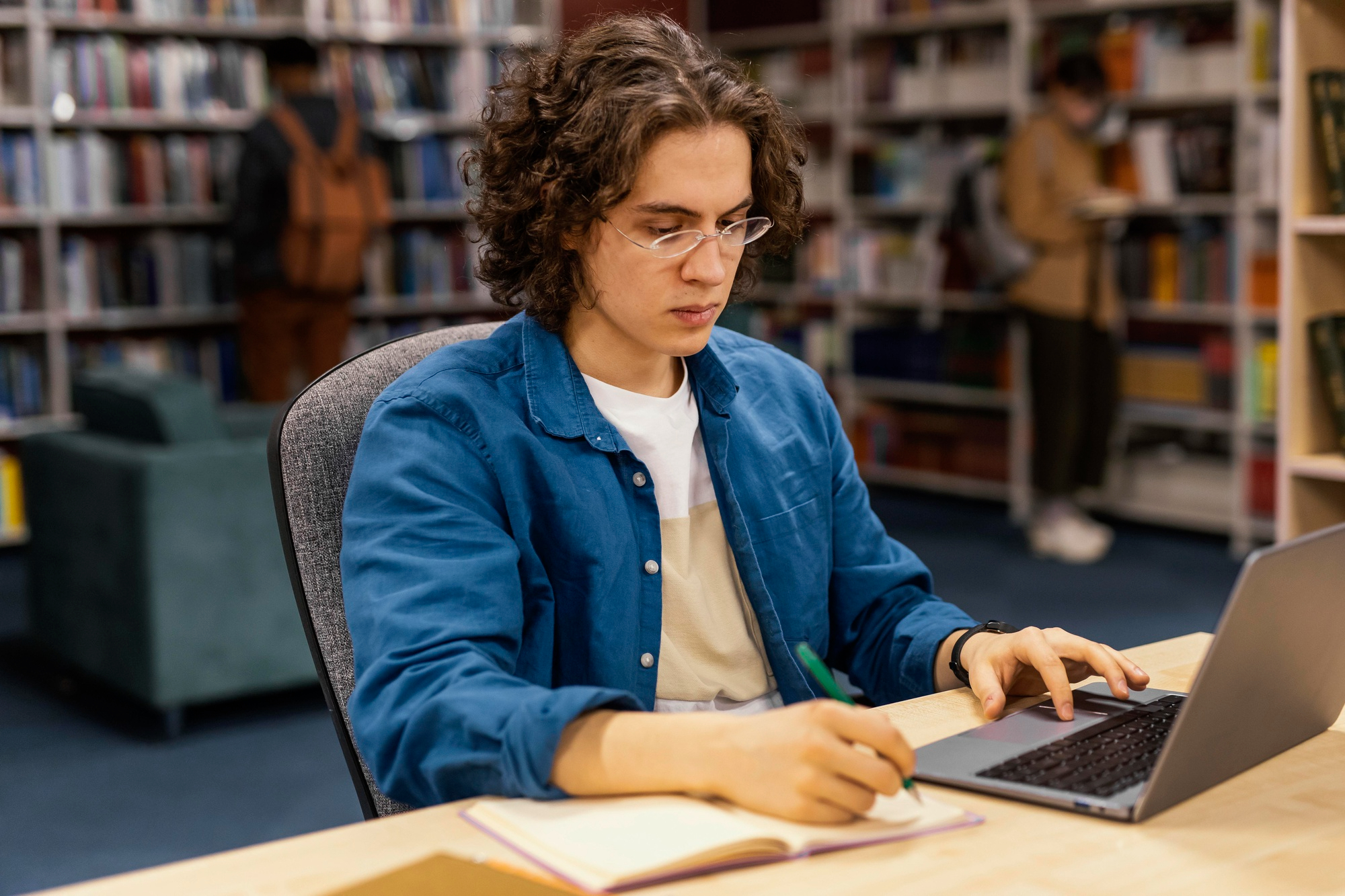 Estudante pesquisando em sites de divulgação científica no notebook durante estudo na biblioteca.
