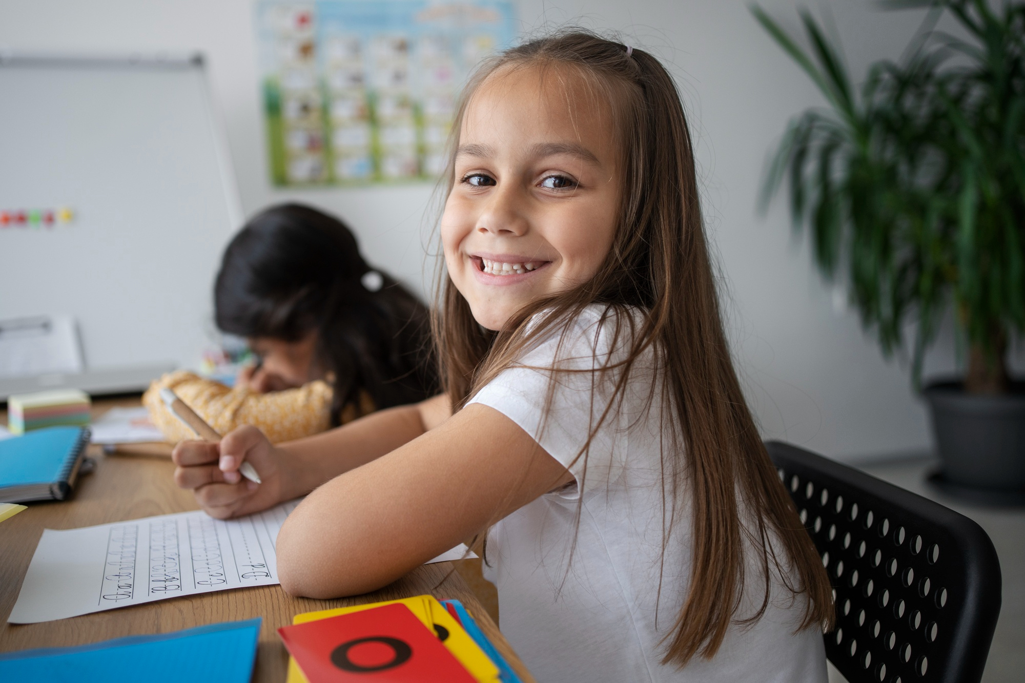 Menina sorrindo em sala de aula durante atividade sobre o Dia Mundial da Língua Portuguesa.