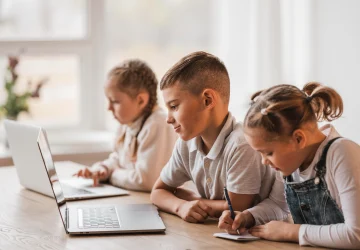 Estudantes em sala de aula usando laptops e caderno em escola que usa Geekie One.